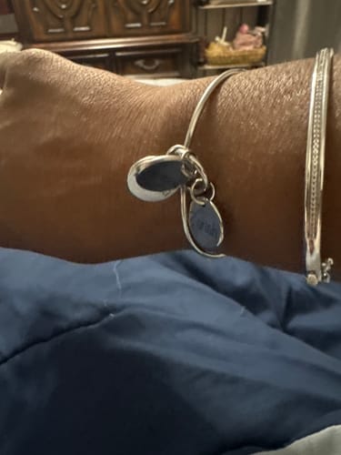 Close-up of a customer's wrist showing the silver Nodum bracelet with dangling pendants.