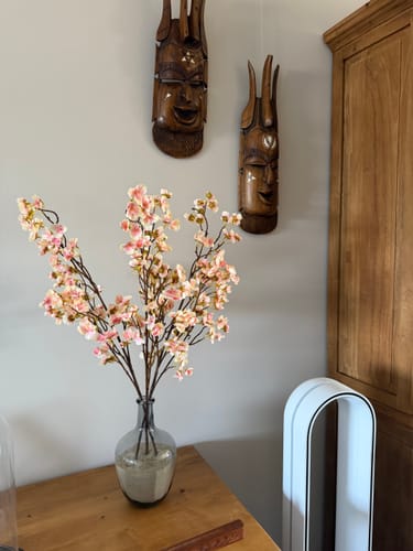 Recensent toont de Oudroze Zijden Bloesems in een donkere vaas op een houten tafel.