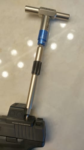 Reviewer using the Mini All-in-One Torque Driver with a T-handle to adjust a screw on a firearm's optic.