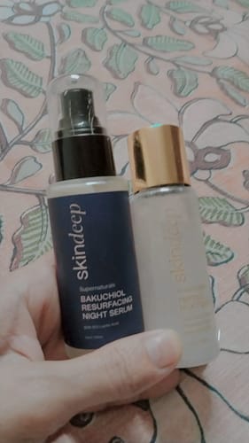 A reviewer's hand holds a bottle of Dream Glaze Peptide Milk Toner and a bottle of Bakuchiol Serum.
