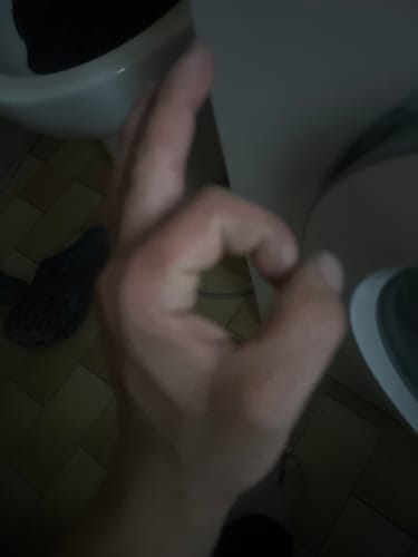 Close-up, blurry photo of a customer's hand making an OK gesture of approval.