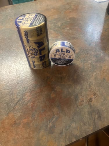 Customer's sleeve and single tin of ALP Chilled Mint Nicotine Pouches on a countertop.