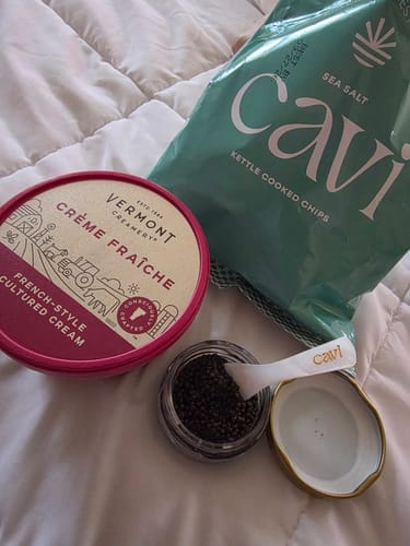 Customer's photo of an open jar of caviar with a Cavi spoon, chips, and crème fraîche.