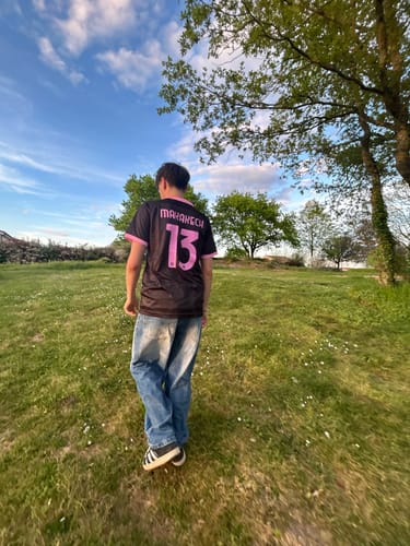 Client de dos portant le maillot noir et rose avec le flocage personnalisé "MARAKECH 13" dans un champ.