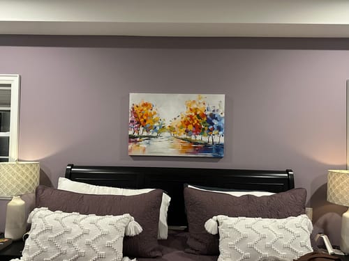 Reviewer's 'Vibrant Reflections' canvas hung above a bed, adding a pop of vibrant color to the purple-walled room.