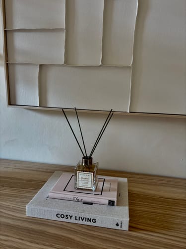 Recensent toont de Istanbul Geurstokjes stijlvol geplaatst op een stapel boeken.