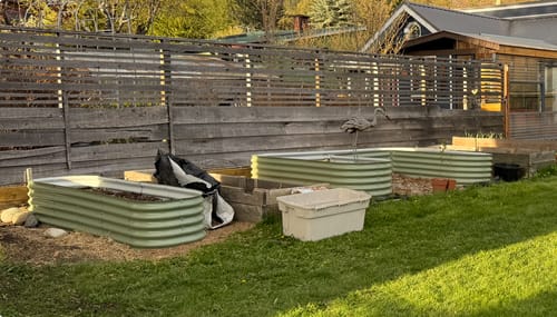 Customer's three new green modular garden beds set up in a backyard, ready to replace old wooden boxes.