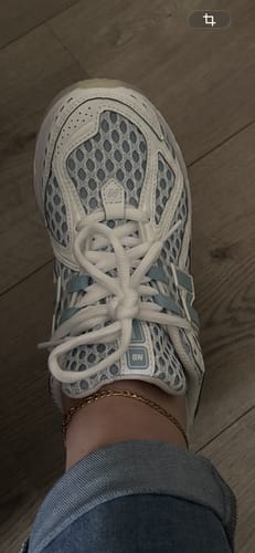 Close-up van de voet van een recensent die de New Balance 1906R Blue Chrome sneaker draagt.