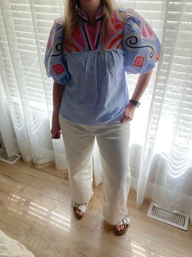 Reviewer standing indoors wearing the cream cropped wide leg denim jeans with a colorful top.