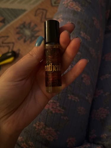 Close-up of a customer holding the Heathenly rollerball perfume bottle in their hand.
