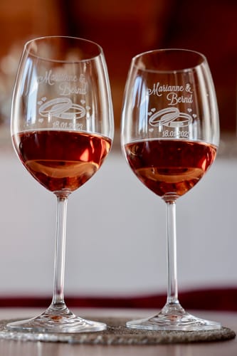 Rezensent zeigt zwei gravierte Leonardo Weingläser mit Roséwein auf einem Untersetzer.