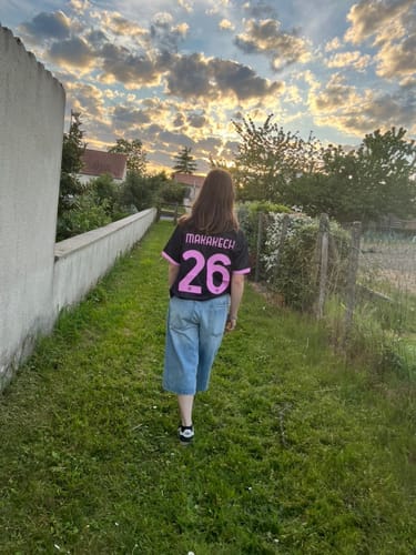 Cliente de dos portant un maillot personnalisé noir et rose avec le flocage 'MAKAKECH 26'.