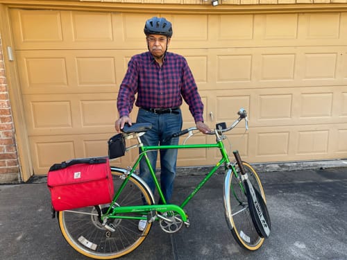 Reviewer standing with his bicycle, which has a pair of K-Swiss sneakers hanging from the front.