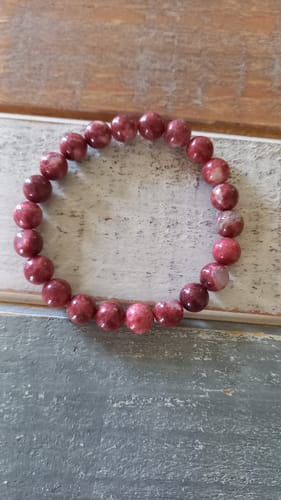 Photo d'un client du bracelet Thulite, montrant les perles roses et rondes sur une table.