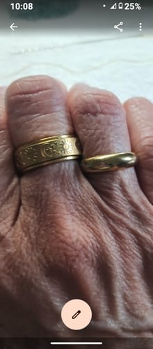 Close-up of a customer's hand wearing the gold Spins Celestial Ring with its engraved pattern.