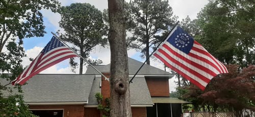 Customer's 1776 to 2026 Betsy Ross Flag flying on a pole attached to a tree, next to a standard US flag.