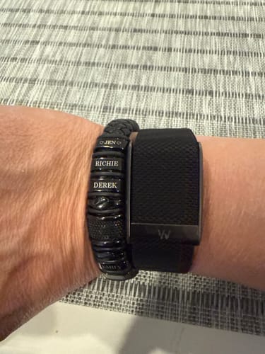 Customer wearing the personalized black bracelet with engraved names on their wrist.