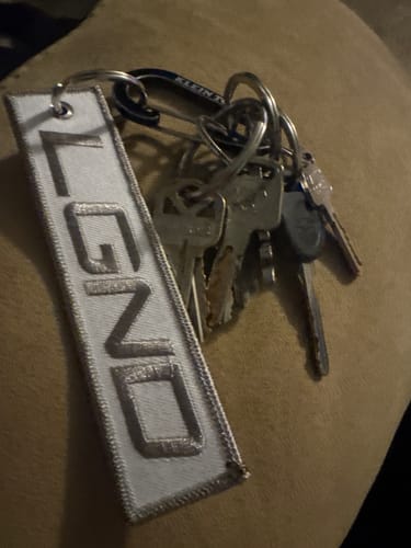 A customer's white Sub-Zero Jet Tag with "LGND" embroidered on it, attached to a set of keys.