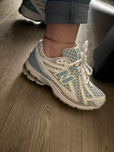 Recensent toont het zijaanzicht van de New Balance 1906R Blue Chrome sneaker, gedragen aan de voet.