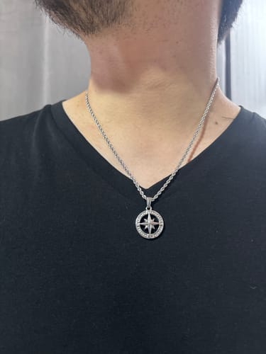 Cliente luciendo el colgante Compass II plateado sobre una camiseta negra.