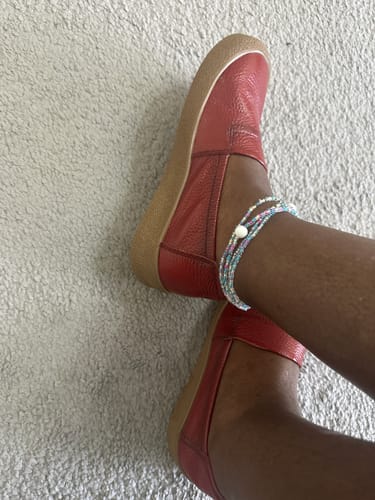 A reviewer wearing the red leather flat shoes, showing the fit and tan soles.