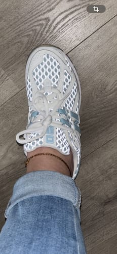 Recensent toont de New Balance 1906R-sneaker met de oplichtende, reflecterende details.