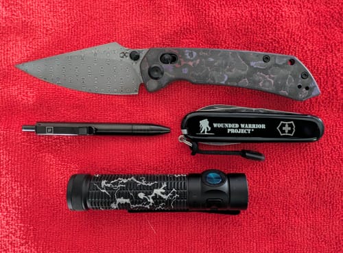 Customer's Kansept Fenrir knife with a Damascus blade and Purple Haze handle, displayed with other everyday carry items.