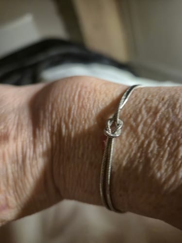 Close-up of a customer wearing the silver Forever Knot Bracelet on their wrist.