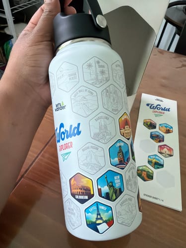 Customer applying the World Explorer Sticker Set to a white bottle, with a sticker sheet visible on the side.
