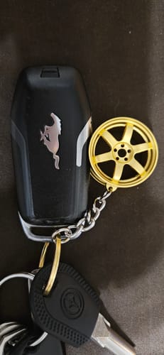 Customer's gold TE Wheel Keychain attached to a black car key fob and other keys.