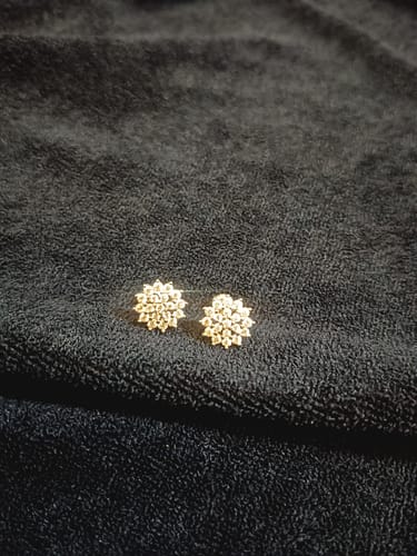 Customer's pair of Silver Zircon Shining Star Studs shown on a dark textured fabric.