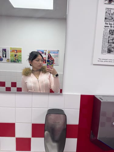 Reviewer wearing the pink Fur Trim Cable Knit Cardigan in a restroom mirror selfie.