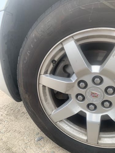 Customer's dark 80Eighty Valve Stem Cap installed on a silver car wheel.