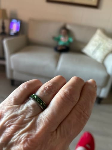 A customer's hand wearing the Viridian ring, showing a close view of the sparkling green crystal inlay.