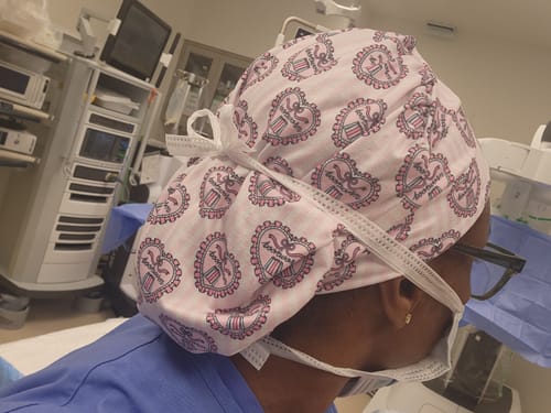 Reviewer in a clinical setting wearing the pink Romantasy DuoStyle Scrub Hat with glasses.