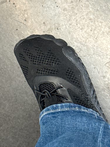 Rezensent trägt den schwarzen Smart Ⅰ Barfußschuh zu Jeans, in einer Nahaufnahme von oben.