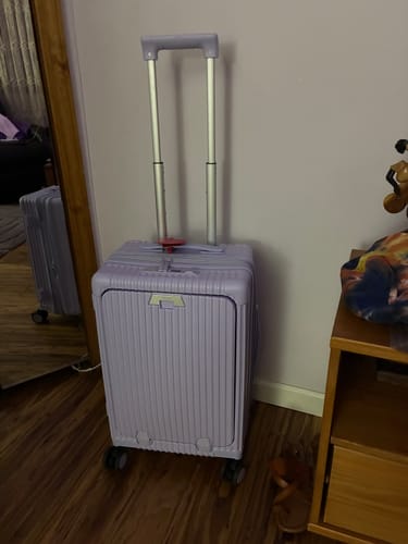 Customer's light purple All-in-One Expandable Carry-On suitcase with its handle extended, standing on a wood floor.