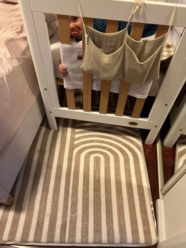 Reviewer's Sahara Lines Mellow Mat on the floor next to a white and timber baby cot in a bedroom.