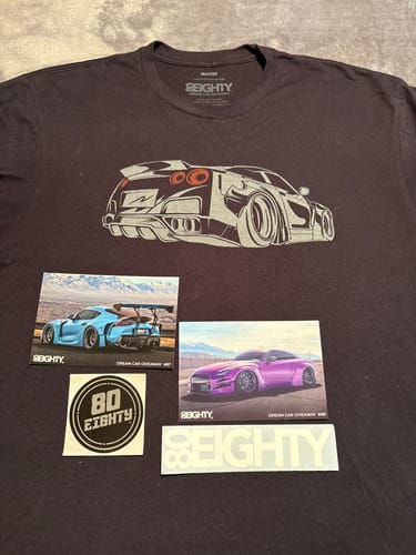 Customer's dark 80Eighty Caboose Shirt with a Nissan GTR graphic, displayed with included stickers and photos.