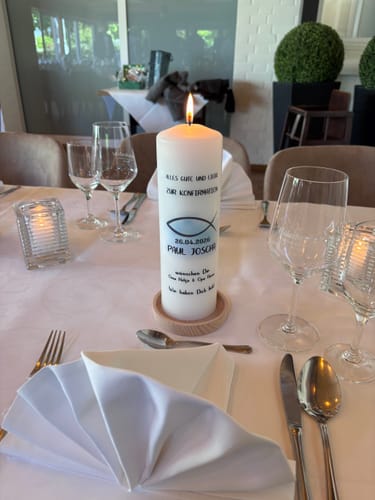 Kundenfoto des hölzernen Kerzentellers mit einer großen, brennenden Kerze auf einem festlich gedeckten Tisch.
