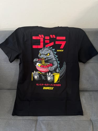 Customer photo of the black RAMEN MONSTER TEE laid flat, showing the back graphic of a monster eating ramen.