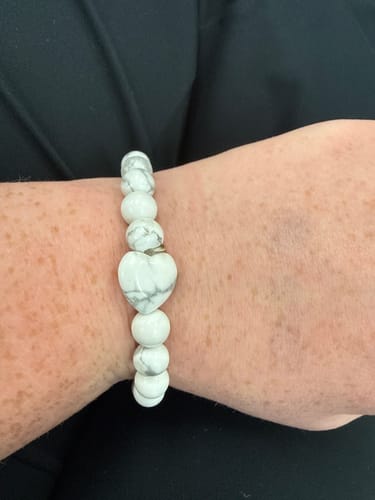 Customer's wrist showing a white crystal bracelet with marbled beads and a prominent heart-shaped bead.