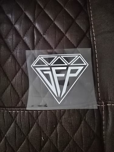 Customer's unapplied Quick Entry sticker with a GFP diamond logo, shown on a dark quilted surface.