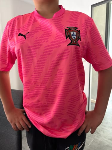 Un client porte le maillot spécial rose du Portugal. Le maillot rose vif est bien ajusté et présente un motif texturé.