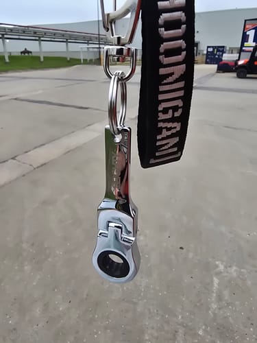Customer's shiny 10mm Wrench Keychain hanging from a carabiner clip outdoors.
