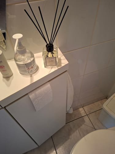 Klant toont de Istanbul geurstokjes op een wit kastje in een badkamer.
