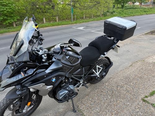 Customer's black Wind Rider Seat Cover installed on a motorcycle parked on a roadside.