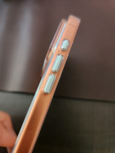 Close-up of a reviewer's Anti Yellow Magsafe Clear Case showing the tactile aluminum buttons on the side.