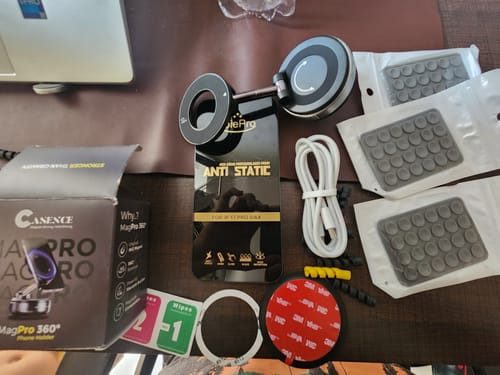 Reviewer's 360° MagPro Magnetic Phone Holder displayed with its box, charging cable, adhesive discs, and other accessories.