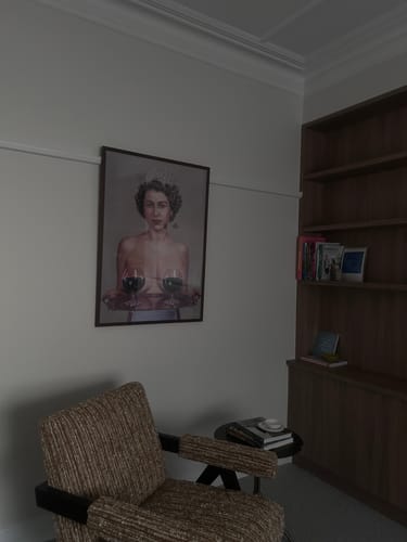 Customer's review photo showing their new, framed artwork of a woman holding wine glasses over a chair.